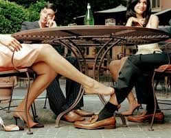 Two couples seated at a table, people closest playing footsie under the table. 