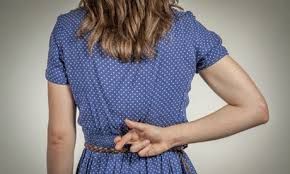 Woman in blue dress with her back to the camera, fingers crossed hidden behind