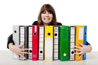 Woman stretching to hold on to many binders