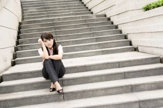 Business woman sitting on the stairs looking dejected