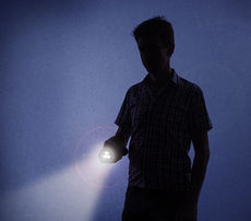 Boy with flashlight at night