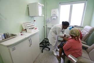 Black woman treating another black woman in a medical office. 