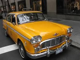 A yellow taxi at a cross walk. 