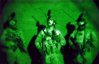 Air Force JTAC scanning the rooftops for snipers during a pre-dawn raid in Fallujah, Iraq, in November 2003. The photo was taken through night vision goggles. (U.S. Air Force photo) 