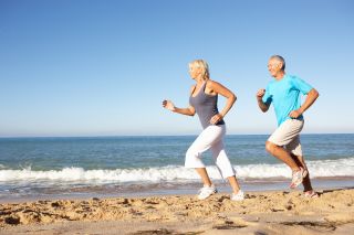 A middle-age couple run along the beach