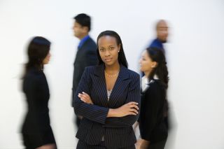 businesswoman standing alone in front of people walking