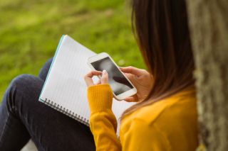 Female college student text messaging in the park