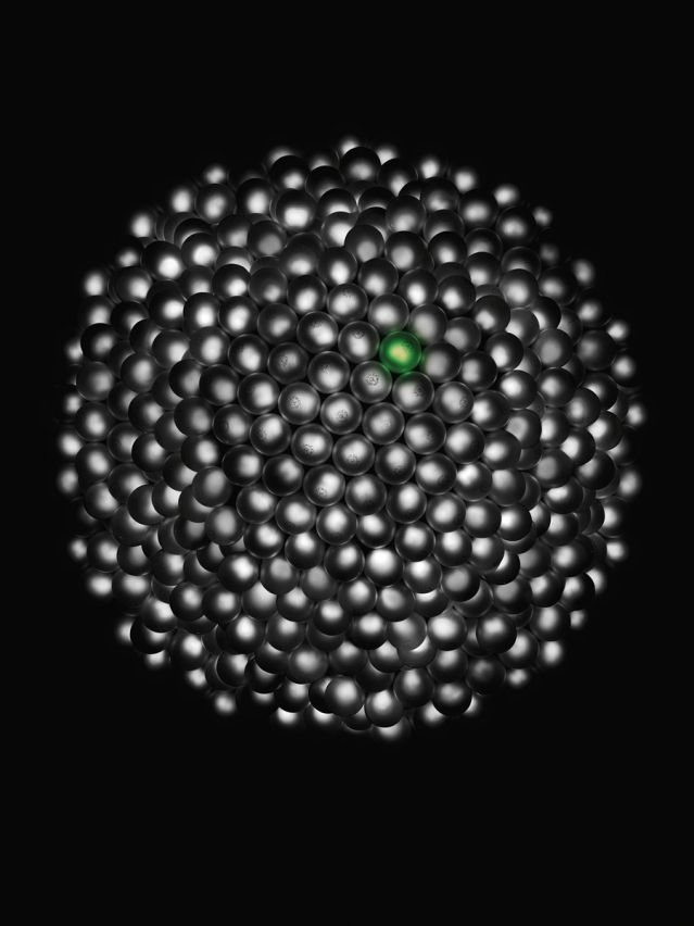 One lightbulb lit green in a bunch of white