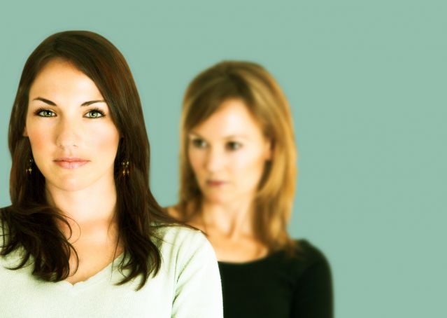 Woman standing behind another woman looking suspicious
