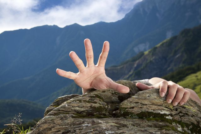 Turning a mountain into a mole hill Hand reaching desperately over the top of a mountain