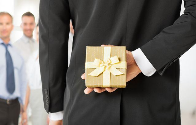 Business man facing team with gift behind his back